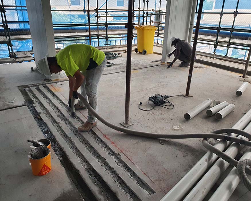 Two man applying carbon fibre structural strengthening to a building concrete floor